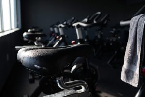 Beads of sweat on the saddle of a spin bike after class, a damp towel hanging on the handlebar
