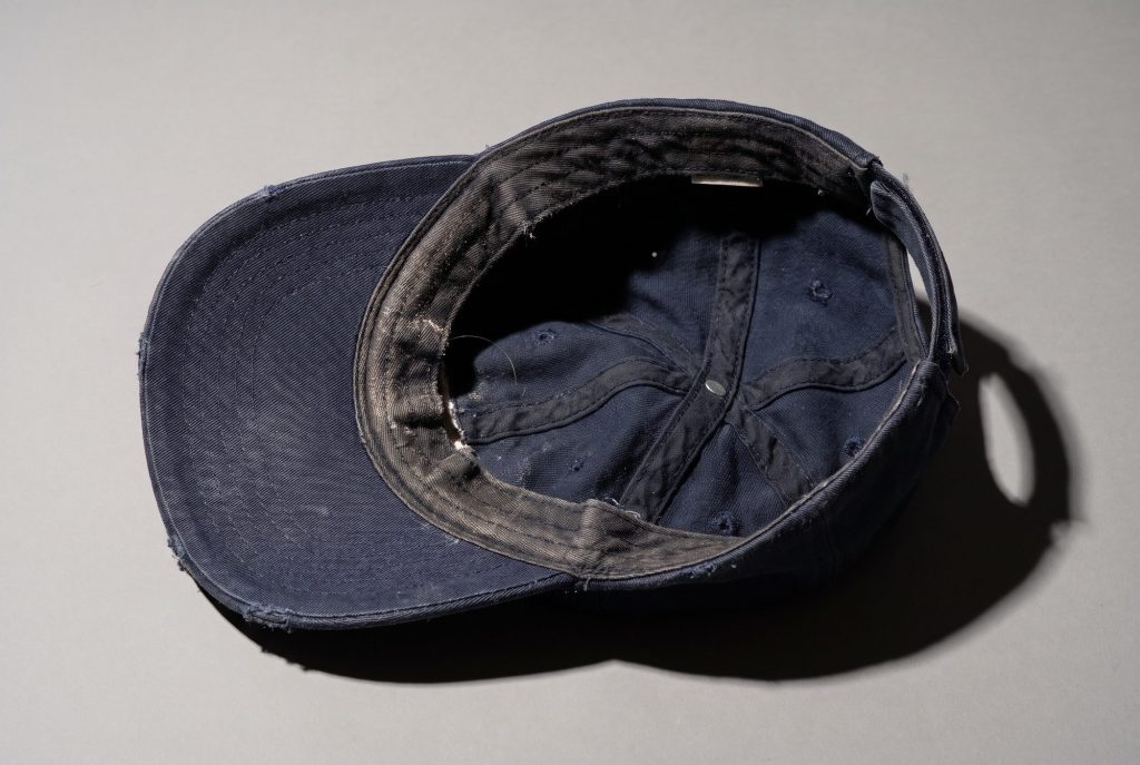 The sweat-darkened inner band of a worn navy baseball cap, seen from above